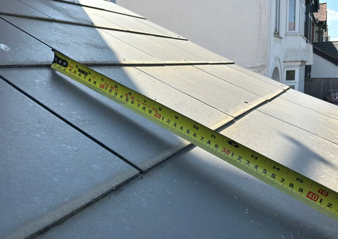 Tape measure placed along a man-made slate roof tile to show its length